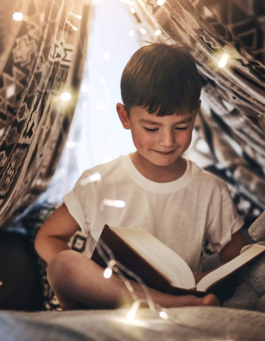 Bambino con libro sotto le luci