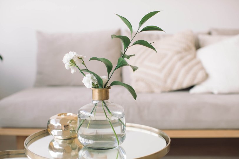 Glass vase with leaves in front of couch and side table